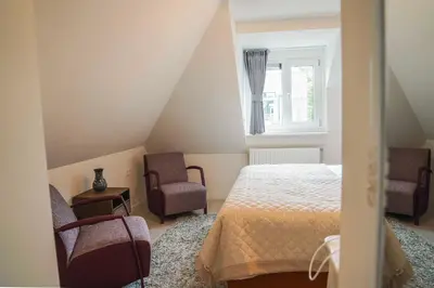 a bedroom with a bed and two chairs and a window at Hotel Koemarkt in Purmerend