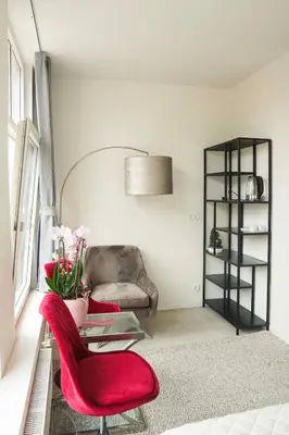 a living room with two red chairs and a table at Hotel Koemarkt in Purmerend