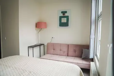 a bedroom with a pink couch next to a bed at Hotel Koemarkt in Purmerend