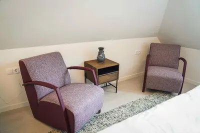 a bedroom with two chairs and a table with a vase at Hotel Koemarkt in Purmerend