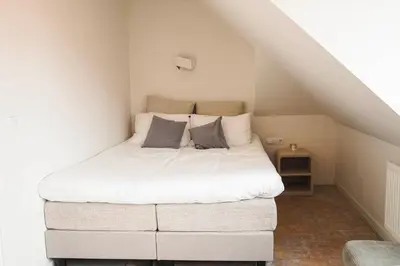 a bedroom with a white bed in the attic at Hotel Koemarkt in Purmerend