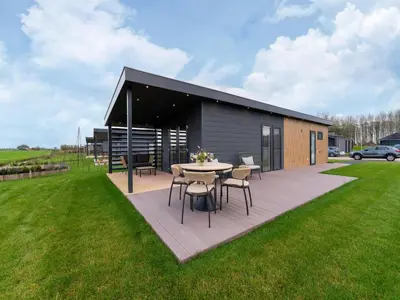 a patio with a table and chairs in a yard at Holiday home in 't Groene Hart on the water in Oud-Ade