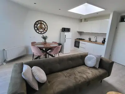 a living room with a couch and a table and a kitchen at Residenz Polderblick in Burgerbrug