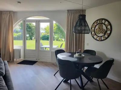 a dining room with a table and chairs and a window at Residenz Polderblick in Burgerbrug