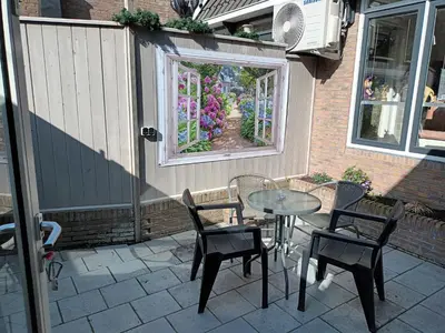 a patio with a table and chairs and a window at De troeter in Monnickendam