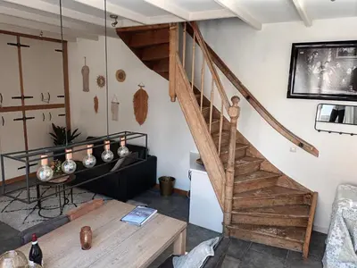 a living room with a wooden staircase and a table at De troeter in Monnickendam
