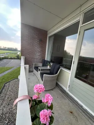 a porch with pink flowers in a vase at Appartement 'Zeeblick' in Burgerbrug