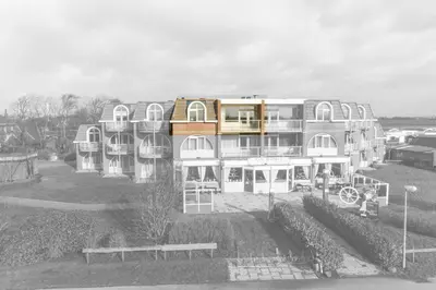 a large white building with a lot of windows at Appartement 'Zeeblick' in Burgerbrug