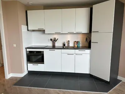 a kitchen with white cabinets and a sink at Appartement 'Zeeblick' in Burgerbrug