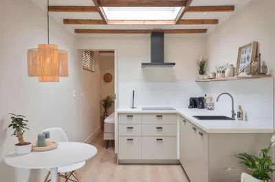 a kitchen with white cabinets and a white table at Beach House at C in Zandvoort