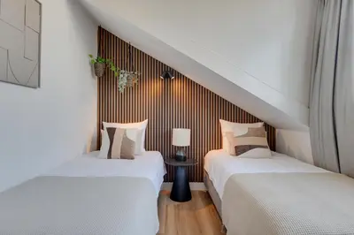 two twin beds in a room with a staircase at Meerzicht 61 - Luxury 4 person apartment in Uitgeest