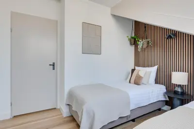 a bedroom with two beds and a door at Meerzicht 61 - Luxury 4 person apartment in Uitgeest