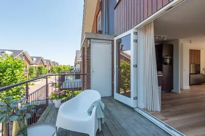 a balcony with a white chair and a door at Meerzicht 61 - Luxury 4 person apartment in Uitgeest