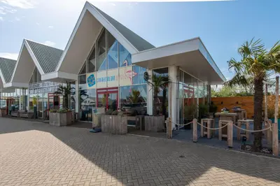 a shopping center with palm trees in front of it at Meerzicht 61 - Luxury 4 person apartment in Uitgeest