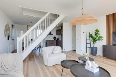 a living room with a white staircase and tables at Meerzicht 61 - Luxury 4 person apartment in Uitgeest