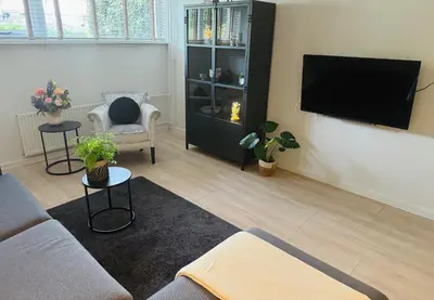 a living room with a couch and a flat screen tv at Souterrain Boslaan Katwijk aan zee in Katwijk aan Zee