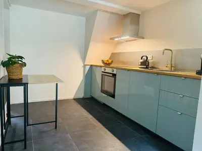 a kitchen with blue cabinets and a table at Souterrain Boslaan Katwijk aan zee in Katwijk aan Zee