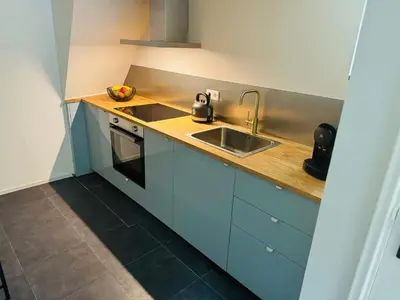 a kitchen with blue cabinets and a sink at Souterrain Boslaan Katwijk aan zee in Katwijk aan Zee