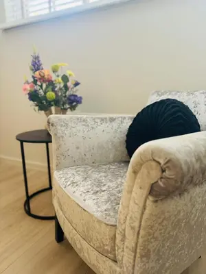 a living room with a chair and a table with a vase of flowers at Souterrain Boslaan Katwijk aan zee in Katwijk aan Zee