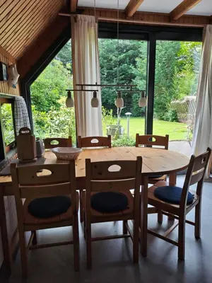 a dining room with a wooden table and chairs at Bungalowpark West Friesland in Opmeer