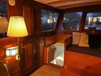 a small room with a lamp and a bed and windows at Woonboot Josja in Amsterdam