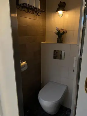 a bathroom with a toilet and a vase of flowers at Woonboot Josja in Amsterdam
