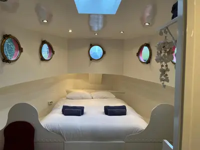 a bedroom with a white bed with two blue pillows at Woonboot Josja in Amsterdam