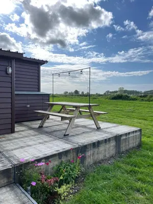 a wooden picnic table sitting on a deck in a field at De Meerkoet in Nieuwe-Niedorp