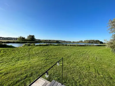 a view of a field of green grass with a pond at De Meerkoet in Nieuwe-Niedorp