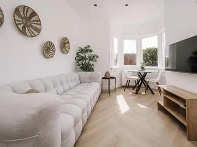 a white living room with a couch and a table at Bella Cottage Zandvoort in Zandvoort