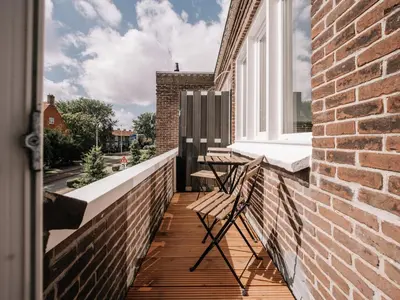 a balcony with two chairs and a window at Bella Cottage Zandvoort in Zandvoort