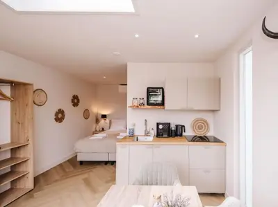 a kitchen with white cabinets and a bed in a room at Ceebee - Free parking in Zandvoort