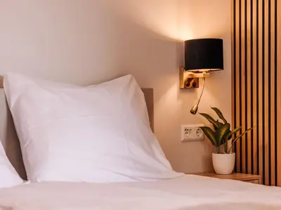 a bed with a white pillow and a lamp and a plant at Ceebee - Free parking in Zandvoort