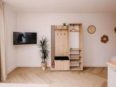 a living room with a wooden cabinet and a tv at Ceebee - Free parking in Zandvoort