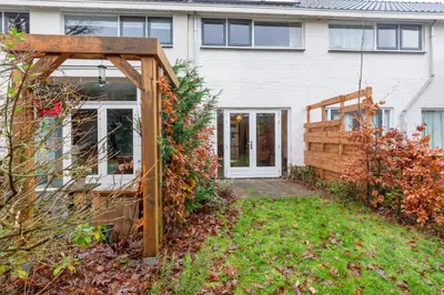 a garden with a wooden pergola in front of a house at Petitville in Austerlitz