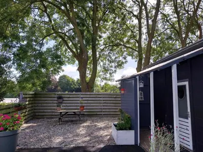 a shed with a bench next to a fence at Vakantiewoning Hem in Hem