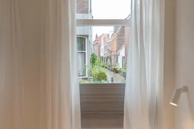 a window with white curtains and a view of a street at Studio Carlos in Haarlem