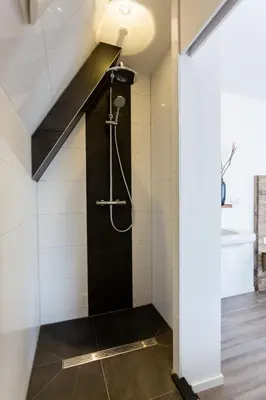a bathroom with a shower under the stairs at Dijkstra Hotels in Bergen