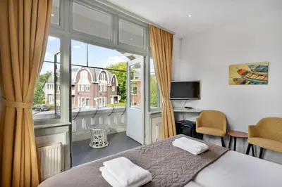 a bedroom with a bed and a large window at Dijkstra Hotels in Bergen