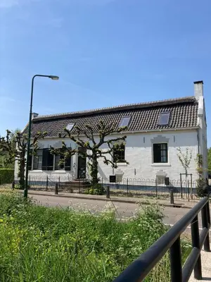 a white house with a fence in front of it at Beautiful renovated Farmhouse in Ankeveen