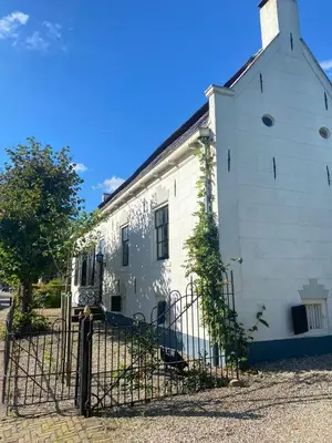 an old white building with a gate in front of it at Beautiful renovated Farmhouse in Ankeveen