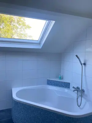 a bathroom with a bath tub with a window at Beautiful renovated Farmhouse in Ankeveen
