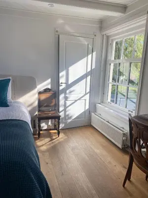 a bedroom with a bed and a chair and a window at Beautiful renovated Farmhouse in Ankeveen