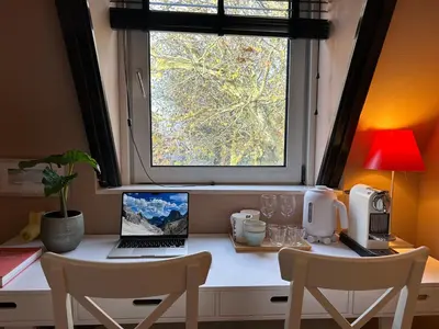 a desk with a laptop computer and a window at Cozy room just outside Utrecht Center, calm & green in Utrecht