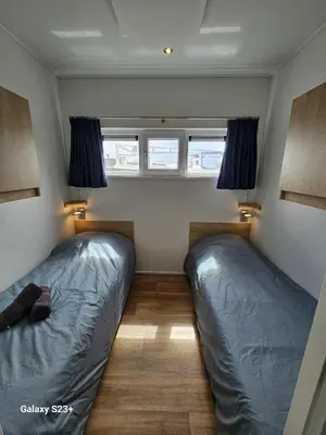two beds in a small room with two windows at Houseboat Tjonger NS003 in Monnickendam