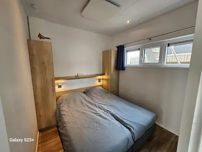 a small bedroom with a bed and a window at Houseboat Tjonger NS003 in Monnickendam