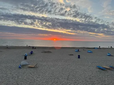 a beach with a sunset and people on the sand at Huisje Aangenaam in Dirkshorn