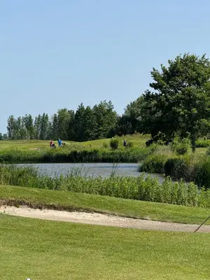 a golf course with a pond and people on a hill at Huisje Aangenaam in Dirkshorn