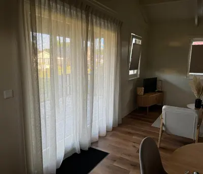 a living room with white curtains and a table at Huisje Aangenaam in Dirkshorn