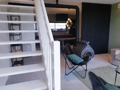 a staircase in a living room with a chair and a table at Luxe stal appartement in Loenen aan de Vecht